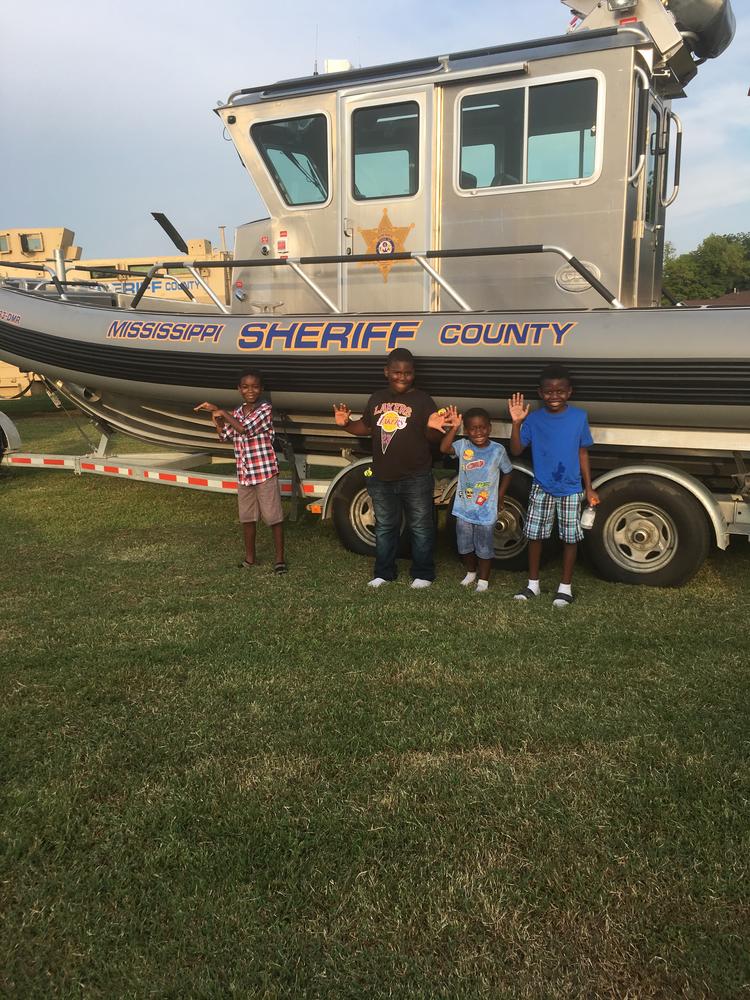 Photo of children standing by sheriff's office boat. 