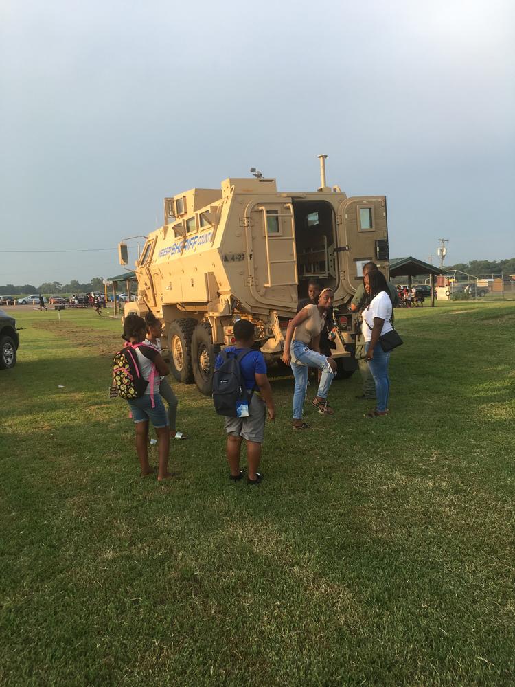 Photo of attendees with armored vehicle. 